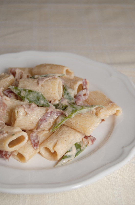 Piatto di rigatoni con taccole speck panna paprika e erba cipollina